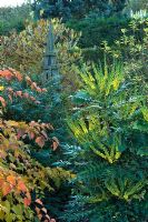 Autumn border with Stephanandra tanakae, Mahonia 'Lionel Fortescue', Hypericum and Magnolia. Obelisk focal point. Mr and Mrs MacLennan, Byndes Cottage, Pebmarsh, Essex