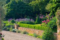 Gravel drive with view over low wall, Buxus - Box hedge, Rosa and Geranium to cottage garden. Mr and Mrs Marshall, Vicarage, Whixley, Yorkshire, UK NGS