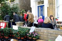 People having tea in a front garden at a plant sale, Hackney, London 