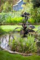 Metal sculpted water fountain by Humphrey Bowden alongisde landscaped pond. Park Terrace, Tillington