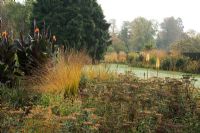 Kniphofia 'Tawny King', Achillea, Canna indica 'Purpurea' and Molinia caerulea 'Heidebraut' - The Savill Garden, Windsor Great Park