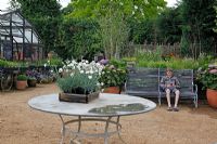 Plants for sale and boy sitting on bench at Petersham Nurseries, Richmond, Surrey
