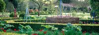 The walled garden with Tulipa, buxus hedges and decorative tripods at West Green House designed by Marylyn Abbott