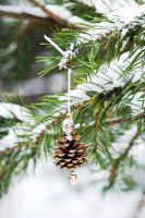 Making pine cone decorations with beads - Finished decoration hanging in a snow covered conifer tree.