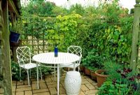 Secluded dining area surrounded by trellis and climbers. Fovant Hut Garden, Wilts