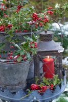 Lantern with red candle and Ilex - Holly in metal buckets on table
