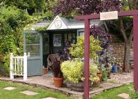 Grey summerhouse and pergola, with Fagus sylvatica 'Purpurea' - Copper Beech, Rosa and Hydrangea. Mill Dene Garden, June Mill Dene Garden, June
