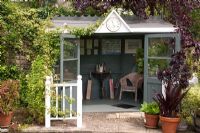 Grey summerhouse, with Fagus sylvatica 'Purpurea' - Copper Beech, Rosa and Hydrangea. Mill Dene Garden, June Mill Dene Garden, June