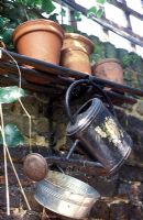 Old watering can and terracotta pots kept outdoors in garden