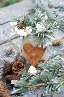 Symphorcarpos albus - Frosted snowberries and pine foliage in a jug with wooden heart and cones
