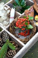 Small rustic wreath with Pyracantha berries in wooden tray with natural Christmas decorations