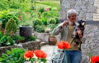 June Blake with her dog Poppy and Papaver orientalis in foreground - June Blake's garden and nursery Co. Wicklow, Ireland 
