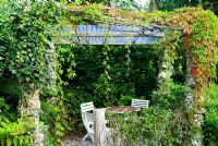Tea shelter with columns constructed from white feldspar, supporting creeper and passion flower - Pinsla Garden, Cardinham, Cornwall