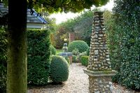 Gravel path and stone obelisk focal point with Taxus baccata - Yew hedge. Silverstone Farm, Norfolk