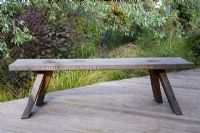 Oak bench with inscription in latin by Marnie Moyle, on raised deck behind Willow foliage, Cotinus, Stipa arundinacea