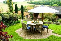 Seating area with umbrella and display of squashes and pumpkins on the table - Bertie's Cottage Garden, Yeoford, Crediton, Devon