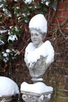 Stone bust laden with snow - Winter Garden and Nursery