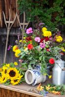 Bouquet of garden flowers, old milk can and hay forks