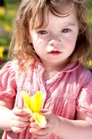 Young girl in red dress holding Daffodil flower in Spring