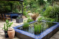 Moroccan style garden with blue tiled pool and drought tolerant plants including Phormium, Musa basjoo and Bamboo