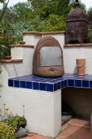 Wood fired oven in Moroccan style garden on tiled outdoor kitchen area with rusty moroccan lantern