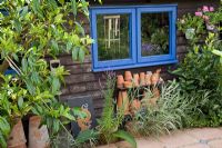 Potting shed with collection of terracotta pots on wrought iron shelves