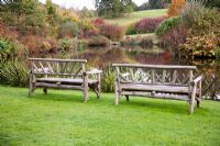 Wooden benches overlooking landscaped lake in autumn - Lady Farm, Somerset