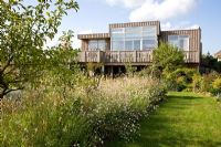 Wooden house overlooking natural planting of Gaura lindheimeri and Malus