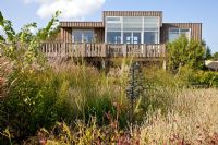 Wooden house overlooking natural planting of Lychnis coronaria