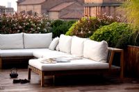 Terrace in Ferrara with sofas with planting 'Abelia compacta', 'Ilex Crenata' and Trachelospermum jasminoides'