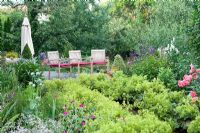 Alchemilla mollis, Rosa 'Rosarium Uetersen', Gysophila, Lychnis coronaria, terrace with wooden chairs and sunshade