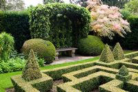 Hedera - Ivy covered port-cullis shaped gazebo at the end of the Knot Garden of clipped Buxus - Box. Bourton House, Bourton-on-the-Hill, Moreton-in-Marsh, Glos, UK