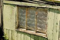 Close up of window of green painted distressed allotment shed 