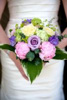 woman holding a bridal bouquet of cream and purple roses and pink peony with hosta leaves