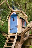 Gothic influenced tree house set amongst branches dotted with masks and birds. The Secret Garden at Serles House, Wimborne, Dorset, UK