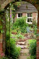 VIew through brick arch in wall to patio - Holbeach Hurn, Lincolnshire, UK,  June
