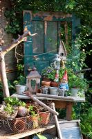Arrangement of antique garden objects with washboard, metal basket, tools, garden gnomes and bird boxes