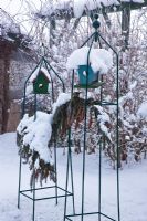 Wooden bird boxes in metal frames covered with snow