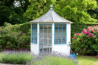 Blue and white summerhouse. Lavandula - Lavender and watering can