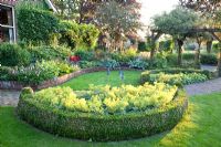 Garden with curved borders, pergolas and semi circular bed of Alchemilla mollis - Ladys Mantle with Buxus edging - Broekhuis Garden
