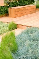 Wooden decking and bench with swathes of Carex and Polypodium vulgare. 'The Green Room' designed by Owen Morgan
