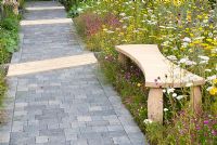 Cobble sett path with wooden bench by wildflower bed in 'A Stitch in Time Saves Nine' garden designed by Daniela Coray. RHS Tatton Flower Garden 2011