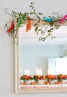 Mistletoe above door with Christmas crackers and decorations on mantelpiece seen in mirror
