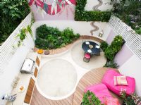 Elevated view of small patio garden with decking, pink chairs, mosaic by Celia Gregory, London.