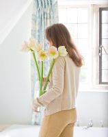 Girl in bathroom holding a vase filled with Amaryllis - Hippeastrum 'Cherry Blossom'