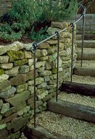  A set of garden steps created using railway sleepers, gravel, dry stone wall and iron handrail 