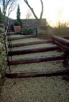 A set of garden steps created using railway sleepers, gravel, dry stone wall and iron handrail 