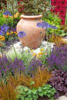 Ornamental terracotta urns in centre of mixed summer borders 