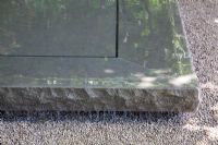 Water gently flowing across a stone plinth in  gravel garden 