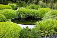 Circular pond surrounded by mounds of clipped Buxus - Box, and  Hakonechloa macra  in 'The Irish Sky Garden' - Gold Medal Winner, RHS Chelsea Flower Show 2011 